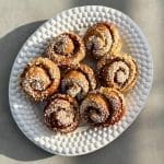 En tallrik med kanelbullar som är dekorerade med pärlsocker.
