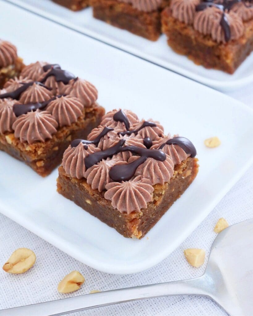 Jannes kärleksmums 17 Bakelse med chokladfrosting och nötter på en vit tallrik.