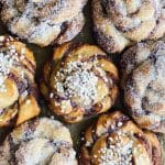 Nygräddade kanelbullar med socker och pärlsocker på toppen, placerade på en plåt.