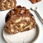 En skiva av daimrulle med chokladbitar och grädde på en tallrik.