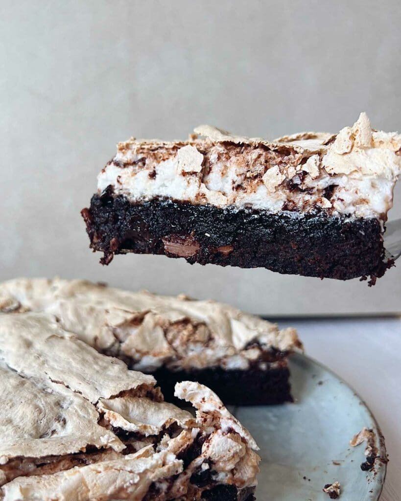 Dammsugarkladdkaka 8 En bit kladdkaka med maräng på en tallrik, med en del av kakan synlig i förgrunden.