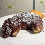 Mini kladdkaka med smält chokladfyllning och pudrat socker på en tallrik.