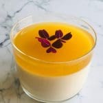 Pannacotta med ett lager av passionsfrukt och dekoration av små blad i en glasbehållare.