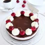 En chokladcheesecake med körsbär och grädde på toppen, serverad på en glasskiva.