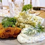 Dubbelpanerad torskfilé serverad med potatismos, ärtor och dillkryddad sås.