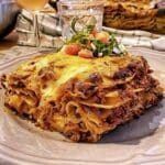 En portion lasagne med köttfärs, ost och grönsaker på en tallrik.