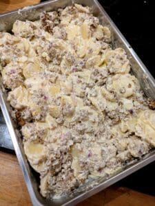 En ugnsform med potatis, köttfärs och gräddfyllning blandat i ett gratängrecept.