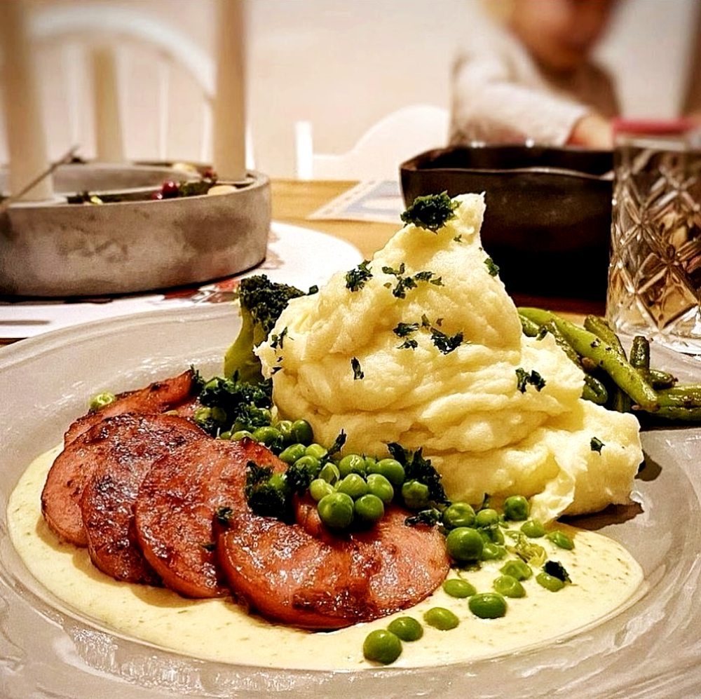 Kolbulle 12 En tallrik med stekt falukorv, potatismos, gröna ärtor och grönsaker.