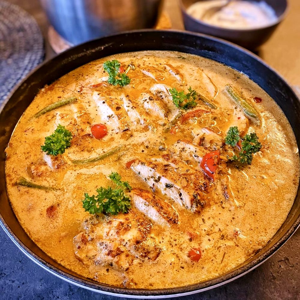 Gratinerad kyckling i ädelostsås 10 En skål med tandoori kyckling i en gräddig sås med grönsaker och örter.