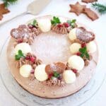 Chokladcheesecake dekorerad med grädde, pepparkakor och bär på en glasskiva.