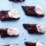 Chokladkolasnittar med vit chokladtopping och krossad polkagris på en bakplåt.