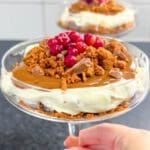 Daimcheesecake i en glasskål med pepparkakssmul och bär på toppen.