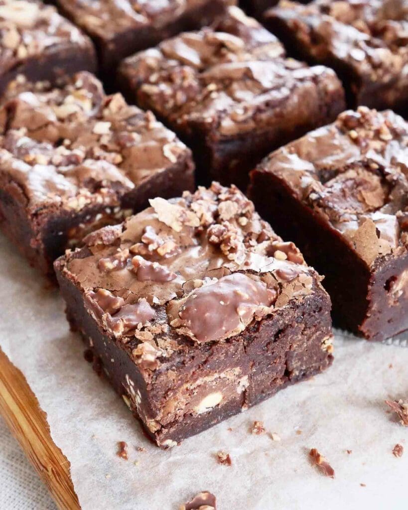 Hasselnötbrownie med nutellafrosting 11 Färdiga Ferrero Rocher brownies skurna i bitar på en bakplåt.