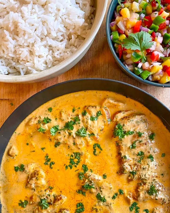 Kyckling Tikka Masala 8 En skål med kycklingfilé i currysås, serverad med ris och en fruktsallad.