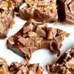 Bit av maraboufudge toppad med krossad Daim på en vit tallrik.