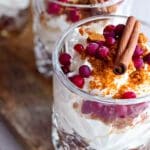 Två glas med no-bake pepparkakscheesecake toppade med grädde, lingon och kanelstänger.