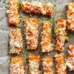 Parmesanrostade morötter på en plåt med bakpapper, täckta med ost och kryddor.