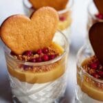 Fyra glas med pepparkakspannacotta toppad med kolasås, krossade pepparkakor och bär.