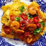 Tallrik med saffranspasta och jätteräkor, dekorerad med chili och grönsaker.