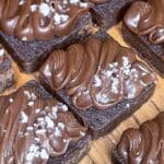Brownies med chokladglasyr och havssalt på en träyta.
