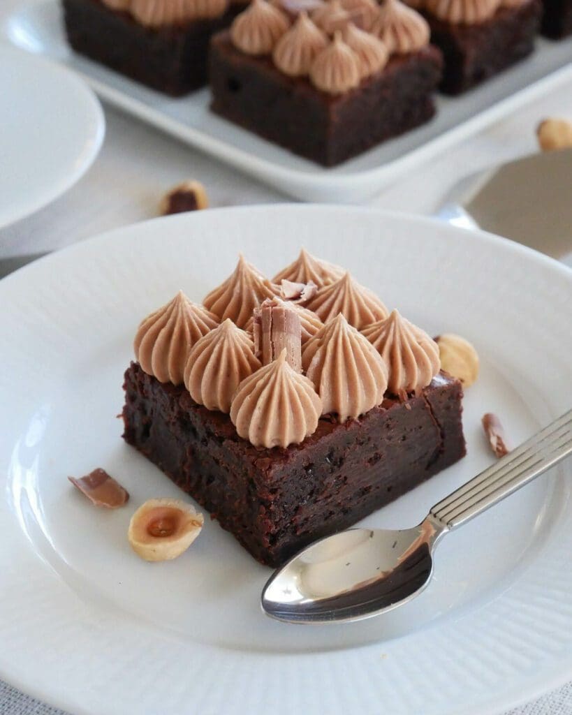 Brownie med mintglasyr 9 En bit brownie med nougatfrosting och dekorationer av choklad och nötter.