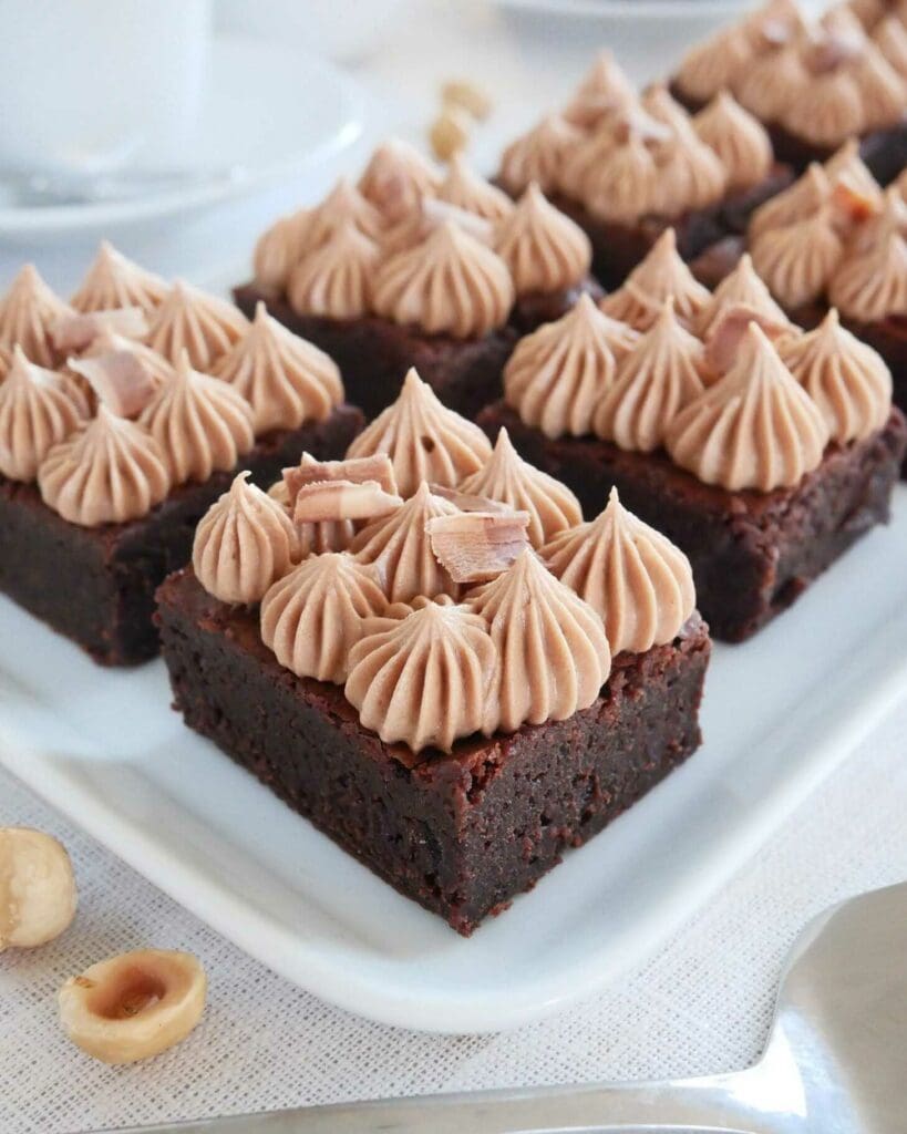 Hasselnötbrownie med nutellafrosting 9 Färdiga brownies med nougatfrosting och dekoration av chokladbitar.