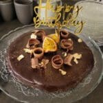 En fudgekaka med en 'Happy Birthday'-dekoration och chokladsnurror på toppen.
