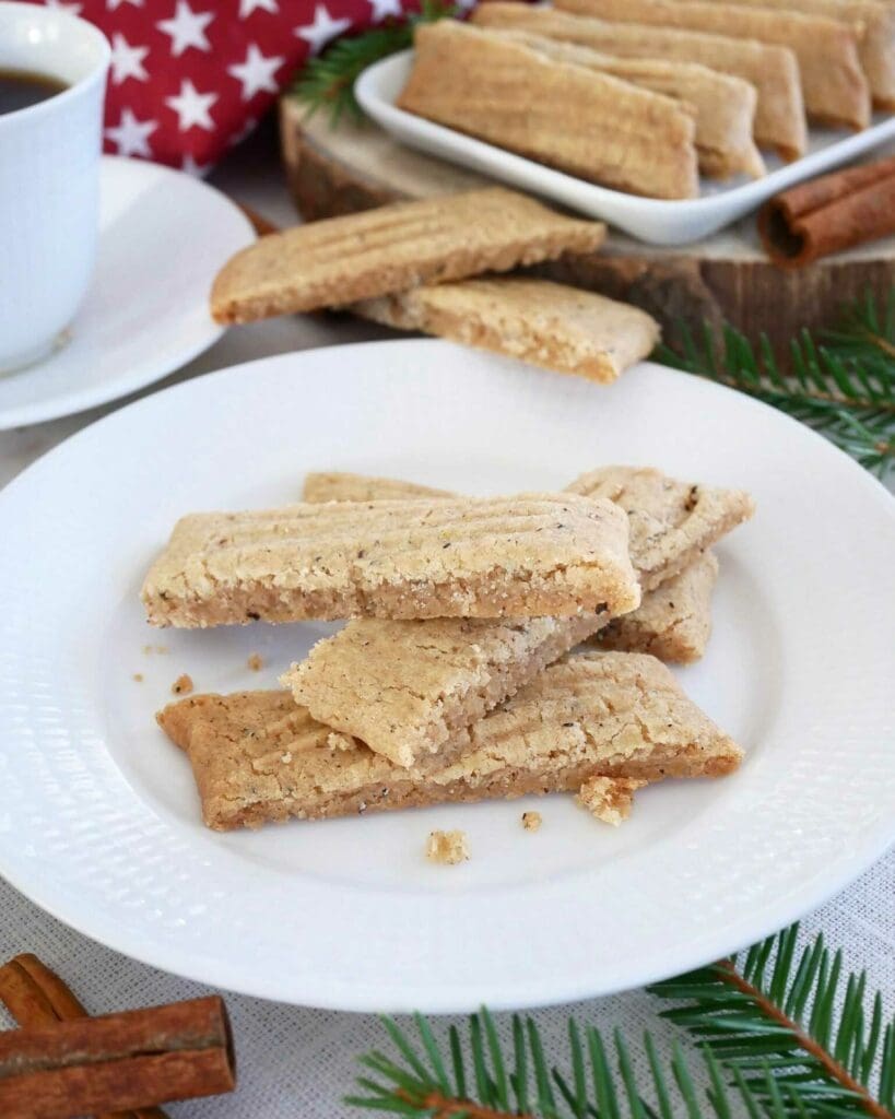 Rabarbersnittar 10 En tallrik med kryddsnittar, en typ av småkakor, med kanelstänger och en kopp kaffe i bakgrunden.