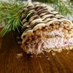 En skivad pepparkaksrulle med lingongrädde på en träskärbräda.