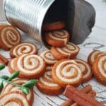 En burk med pepparkakssnurror som ligger utspridda på ett bord.