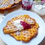 En tallrik med saffransvåfflor toppade med grädde och sylt.