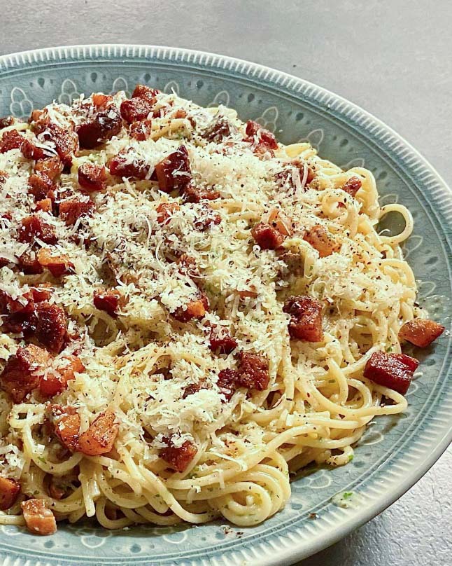 Linsbollar med spagetti i tomatsås 7 Tallrik med spaghetti carbonara toppad med bacon och parmesanost.