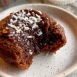 En kladdmuffin med chokladtopping och kokosflingor på en tallrik.