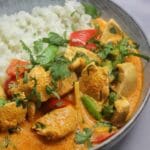 Skål med röd thailändsk curry innehållande kyckling, grönsaker och ris.