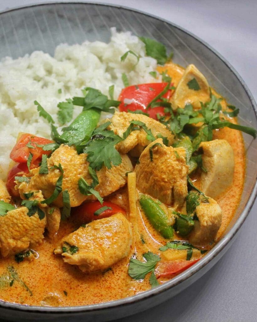 Fransk kycklinggryta 5 Skål med röd thailändsk curry innehållande kyckling, grönsaker och ris.
