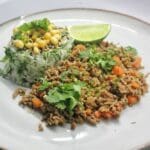 En tallrik med asiatisk köttfärssås, ris och limeklyfta.