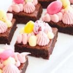 Glutenfria brownies dekorerade med rosa grädde och färgglada godisägg.