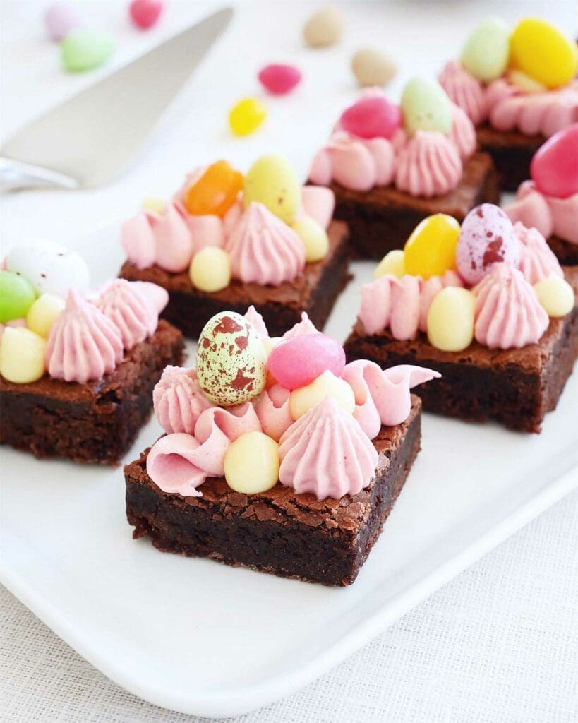 Påskprinsesstårta i glas med lemon curd 12 Glutenfria brownies dekorerade med rosa grädde och färgglada godisägg.