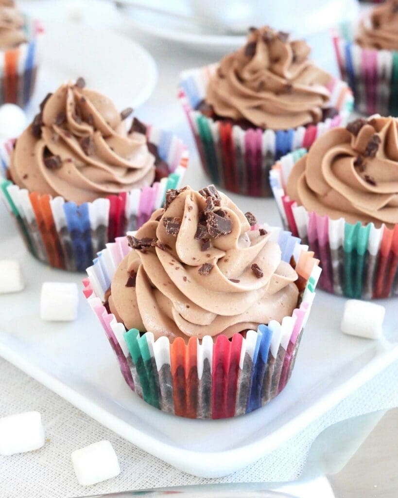 Blåbärsmuffins 7 Muffins med chokladfrosting och dekoration av chokladbitar i färgglada muffinsformar.