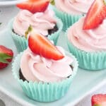 Fyra kladdkakemuffins med rosa glasyr och skivor av jordgubbar på toppen.
