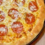 En pizza med pepperoni och smält ost på en rund botten.