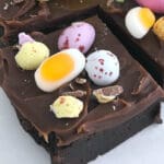 En bit chokladbrownie dekorerad med färgglada godisar och chokladbitar.