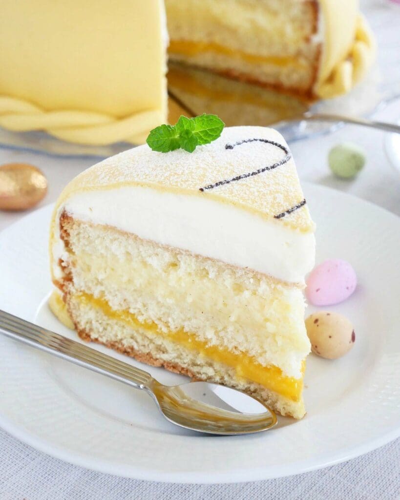 Påskprinsesstårta i glas med lemon curd 11 Skiva av påskprinsesstårta med grädde, sylt och dekoration på en tallrik.