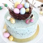 En påsktårta med grön frosting, dekorerad med chokladägg och ett fågelbo av choklad.