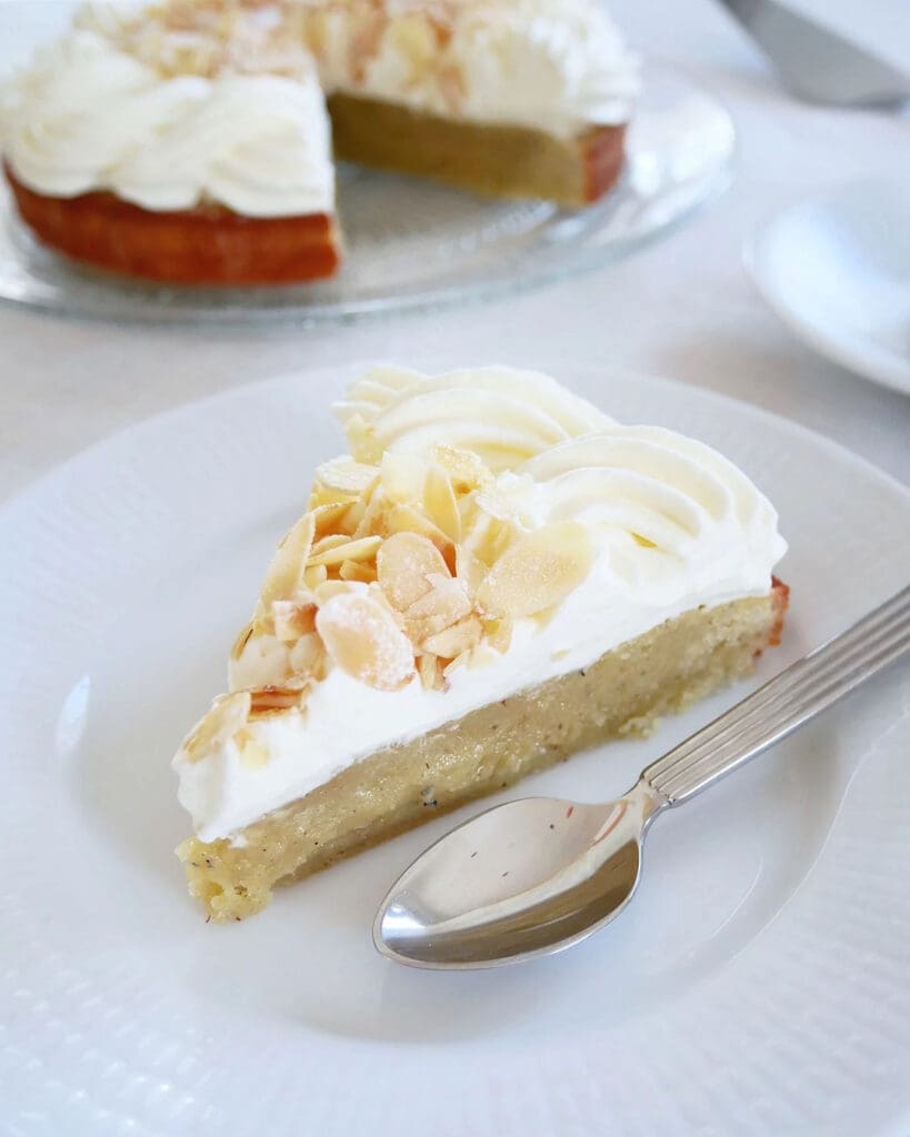 Elinas citronkladdkaka 8 En bit semmelkladdkaka med grädde och mandel på en vit tallrik med sked.