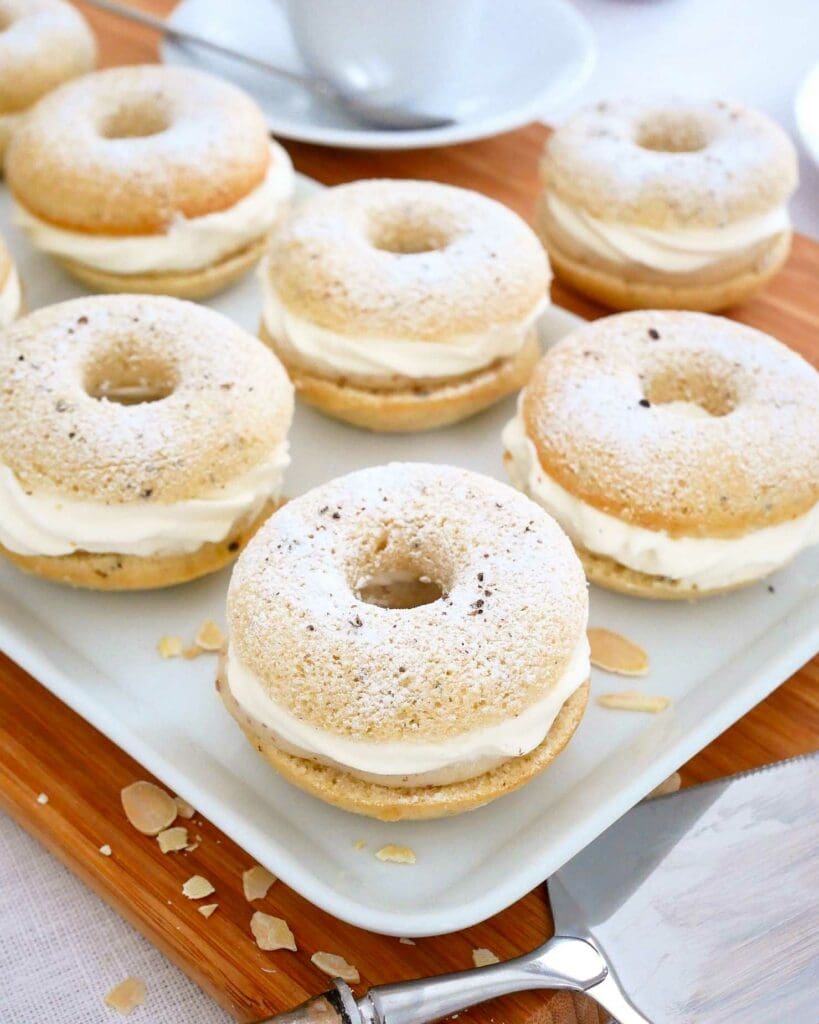 Donuts 9 En tallrik med semmelmunkar fyllda med grädde och pudrade med florsocker.