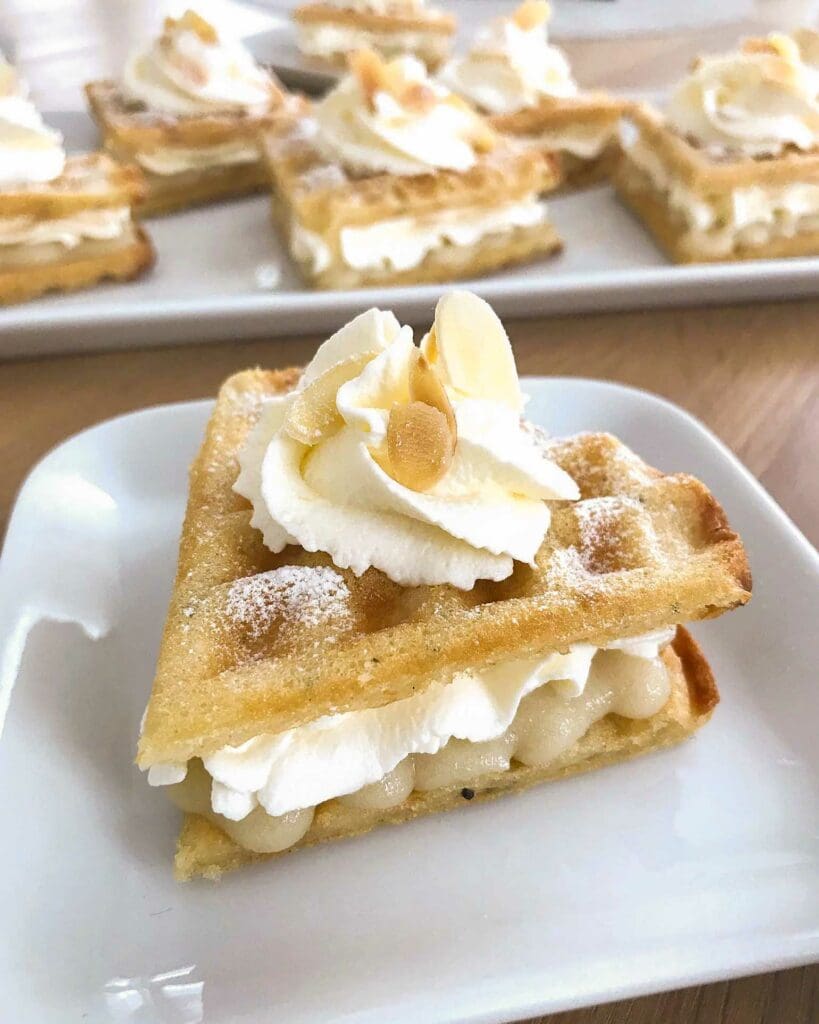 Glutenfria bananvåfflor 9 En bit semmelvåffla med grädde och mandel på en vit tallrik.