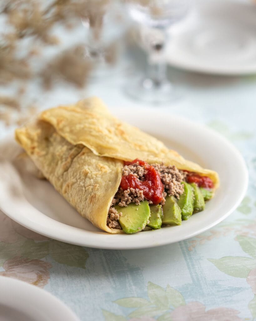 Knådfria frallor 7 Tunnbröd fyllt med köttfärs, avokado och tomatsås på en vit tallrik.