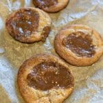 Fyra kakor med dulce de leche-fyllning på en bakplåt med bakpapper.