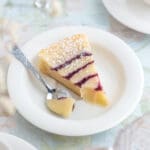 En bit hallongrottskladdkaka på en vit tallrik med en sked bredvid.